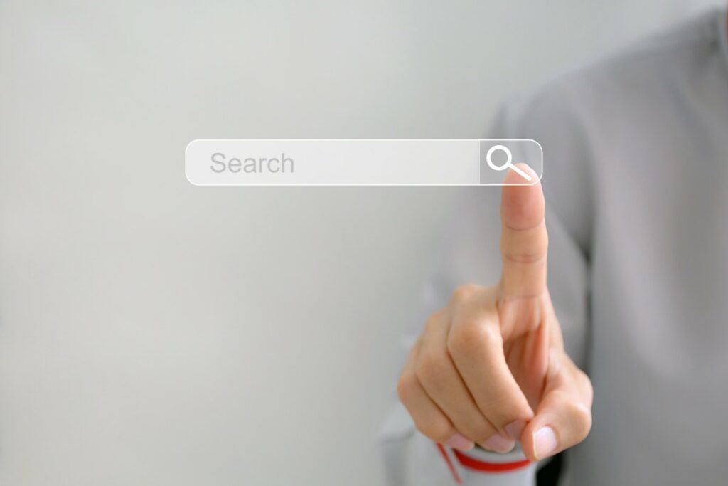 Search engine search bar and a finger hovering over the search button in order to find the perfect way to apply for a job