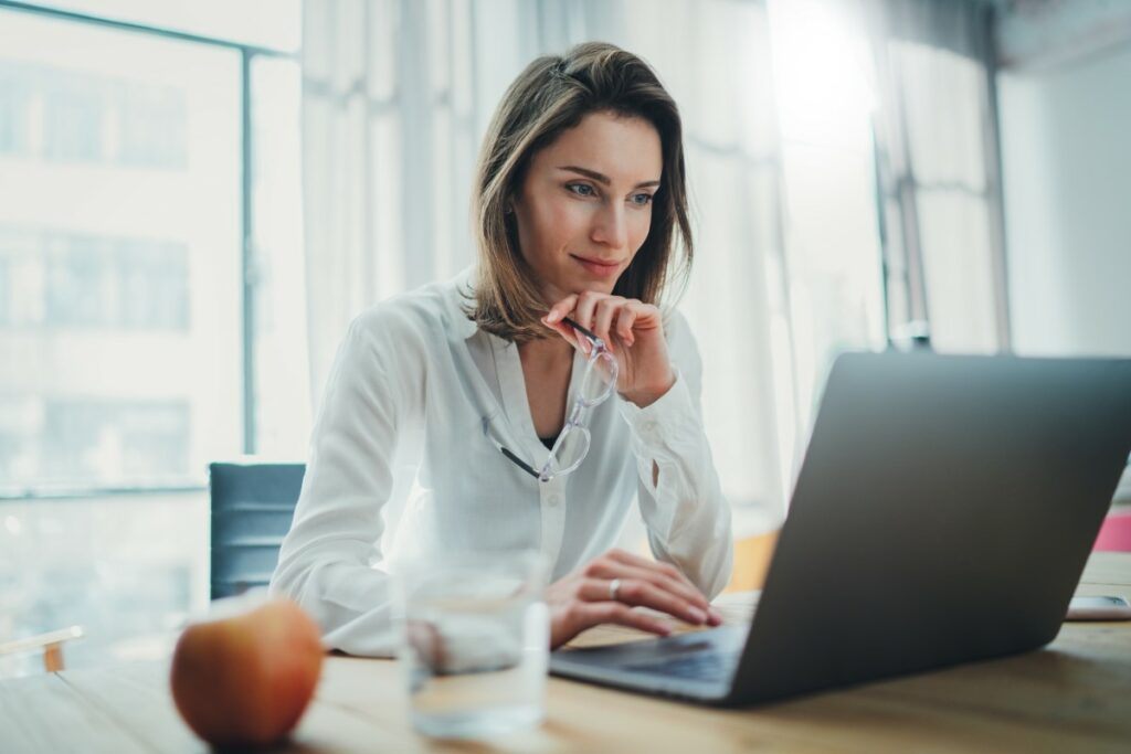 Woman sitting at a desk in front of a laptpo reading about the highest paid bachelor degree jobs