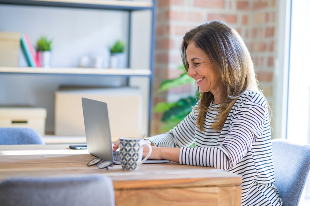 middle aged happy woman looking at her laptop