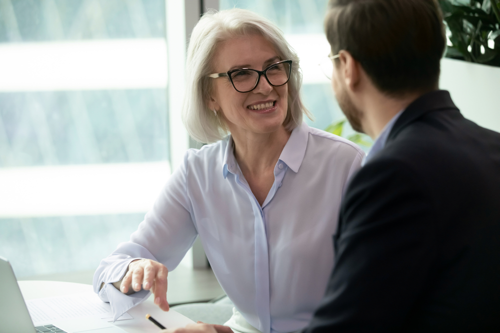 Smiling,Middle-aged,Female,Employee,Talk,Brainstorm,With,Male,Colleague,At