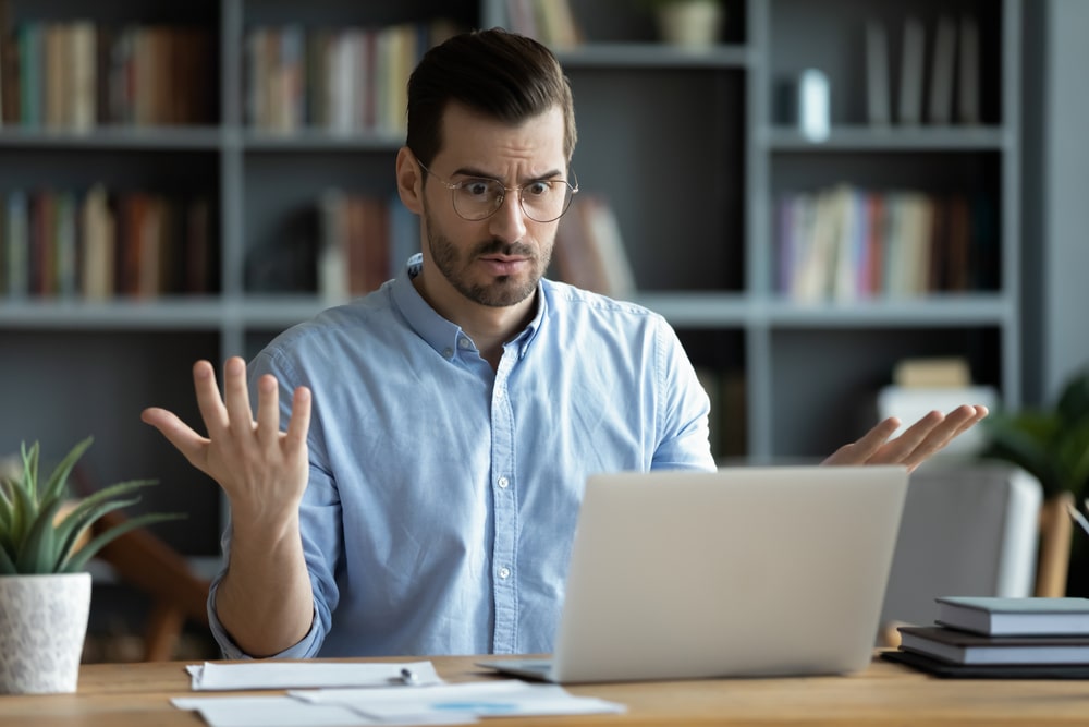 a man looks at his laptop and makes a questioning face