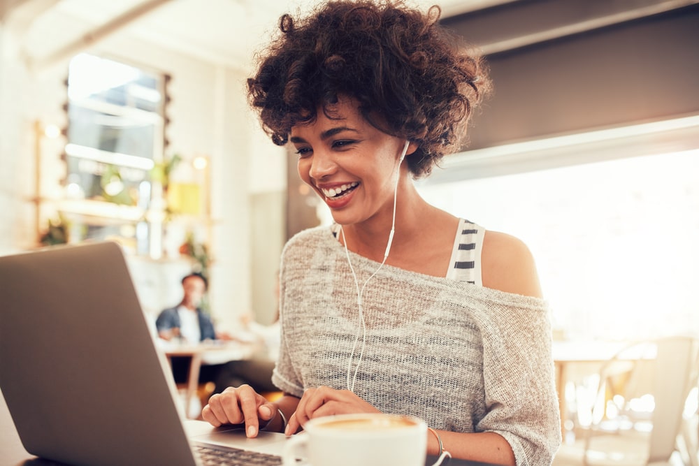 A young woman sits in front of her notebook and smiles