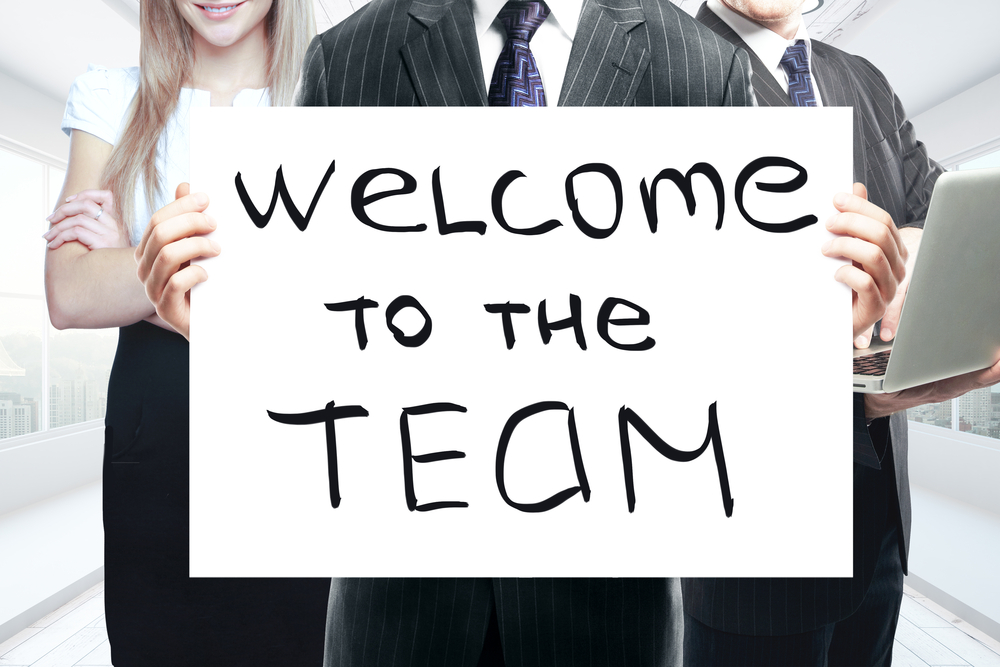 Businesspeople,Holding,Whiteboard,With,'welcome,To,The,Team',Text.,Teamwork