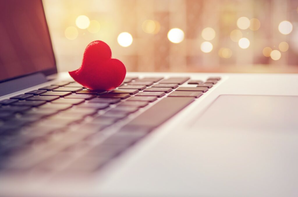 red heart on the keyboard of a laptop, background sparkling with light