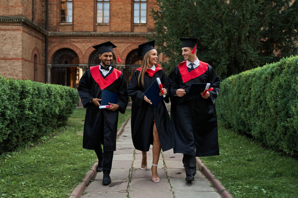 Three graduated friends walking on campus on graduation day